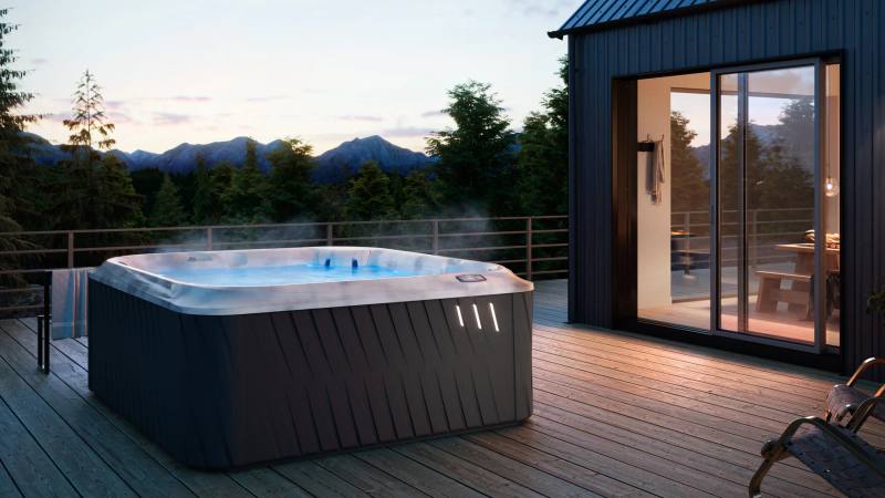 Spa Jacuzzi J-275 para 6 pessoas instalado em um deck de madeira, com iluminação ao entardecer